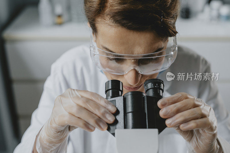 女科学家/实验室技术员使用显微镜进行研究
